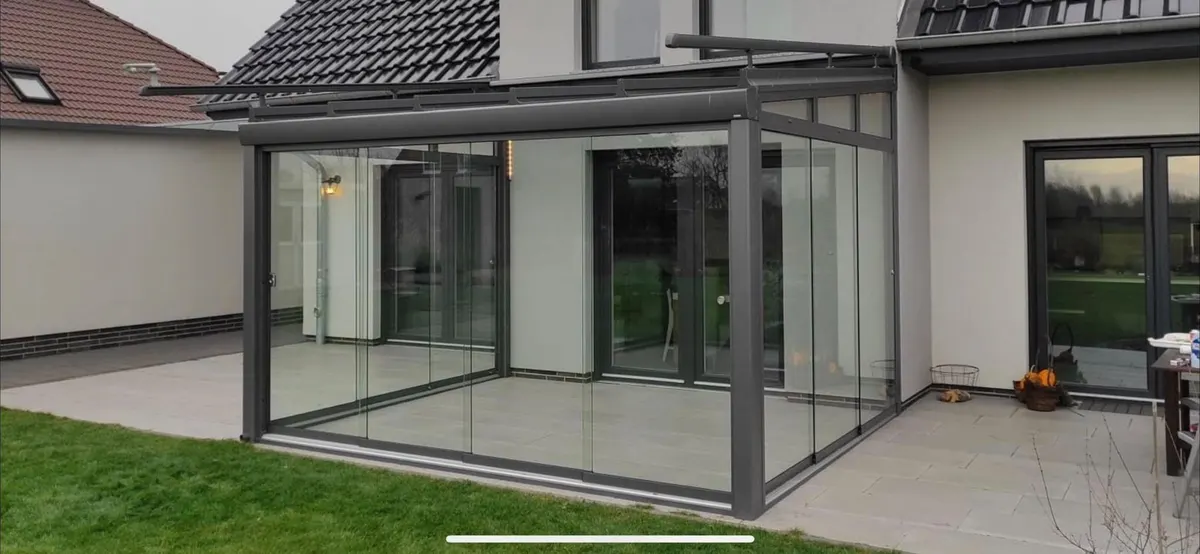 Glas-Schiebewände unter Terrassendach an weißem Haus