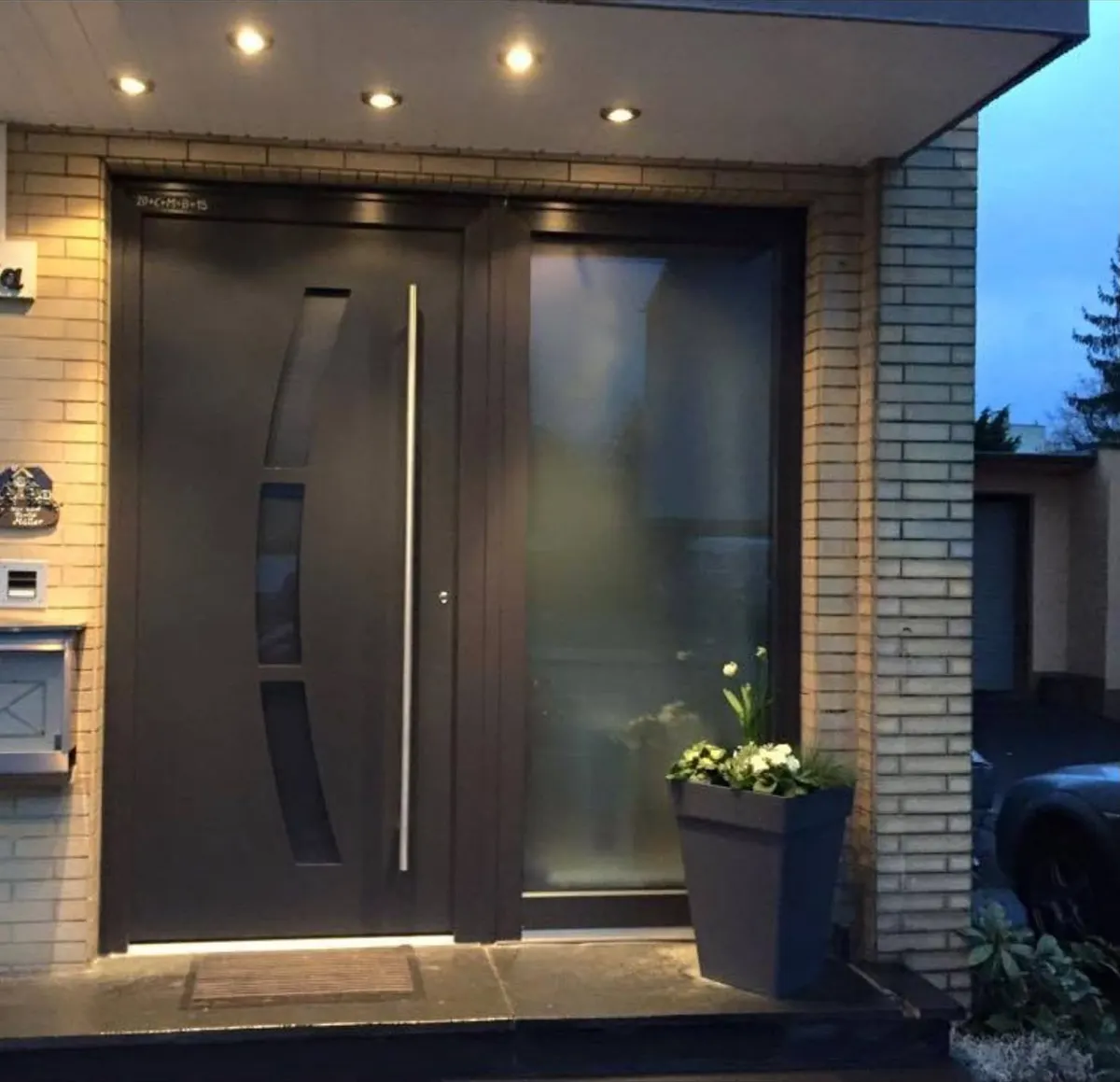 Dunkle Haustür mit Glasseitenteil und Beleuchtung