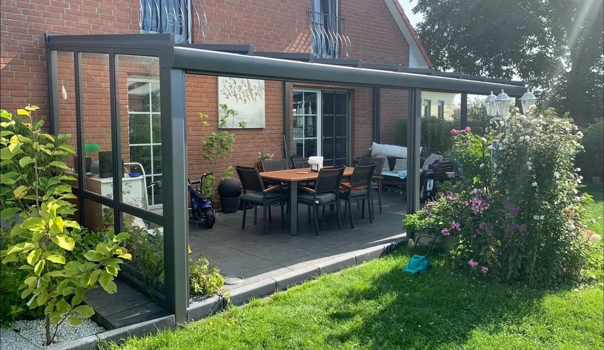 Anthrazitfarbenes Terrassendach mit Glaseindeckung vor Klinkerfassade